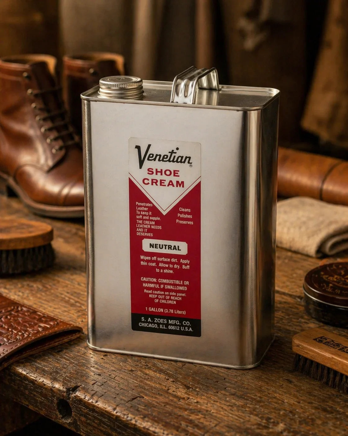 Venetian Shoe Cream gallon can on rustic wooden table with leather boots and shoe care brushes