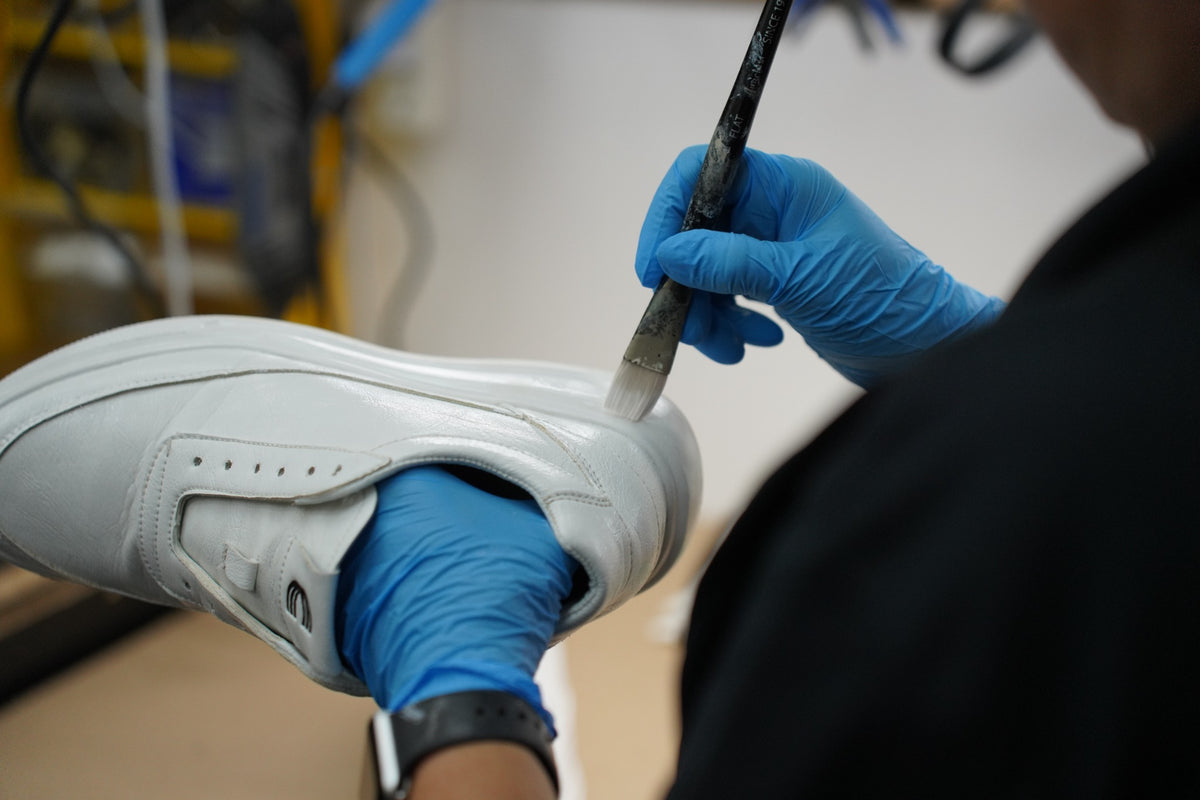 ShoeMedic technician restoring a white leather sneaker by hand